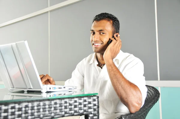 Hombre indio con portátil hablando por teléfono — Foto de Stock