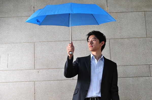 Asiático joven hombre con azul paraguas dentro — Foto de Stock