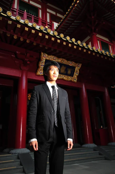 Ασιατικές νεαρός άνδρας, που στέκεται μπροστά από ένα ναό — Φωτογραφία Αρχείου