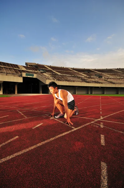 Asian Chinese man preparing his run at the stadium — Stock Photo, Image