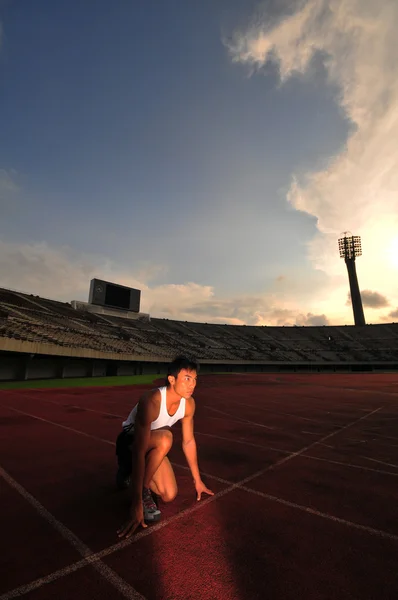 Asian Chinese man preparing his run at the stadium — Stock Photo, Image