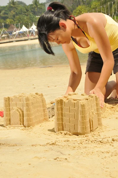 Азиатская китайская девушка делает песчаный замок вдоль пляжа — стоковое фото