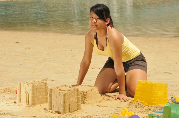 Azjatycki chiński dziewczynka co zamek z piasku wzdłuż plaży — Zdjęcie stockowe