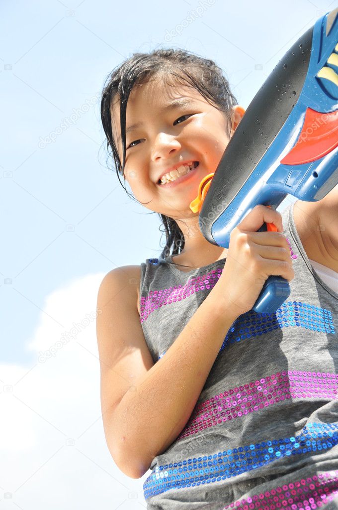 Asian chinese young girl playing with a water gun