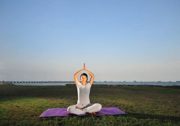 Asiatisk kinesisk Dam utöva yoga nära havet — Stockfoto