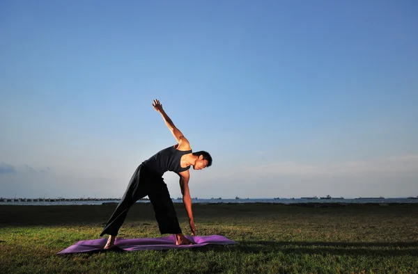 Asiatischer Chinese macht Yoga in einem Garten am Meer — Stockfoto