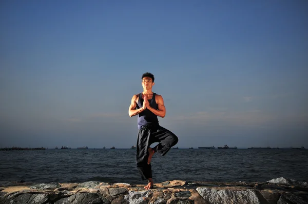 Asiatisk kinesisk man utövar yoga på stranden — Stockfoto