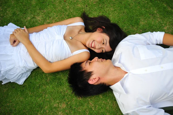 亚洲的中国夫妇，躺在草地上，有各种各样的表情 — 图库照片