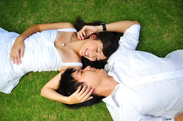 Asijské čínský pár ležící na trávě s různými výrazy — Stock fotografie