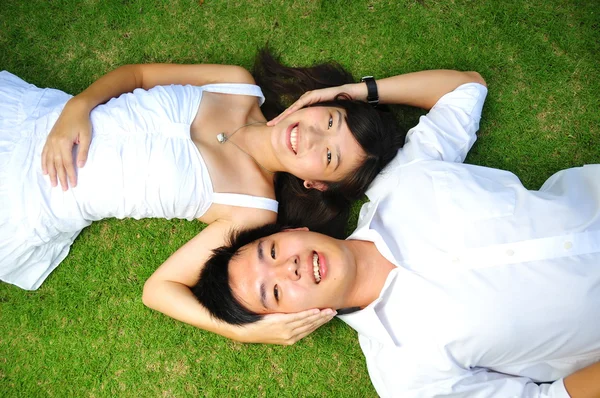Asiático chinês casal deitado na grama com várias expressões — Fotografia de Stock