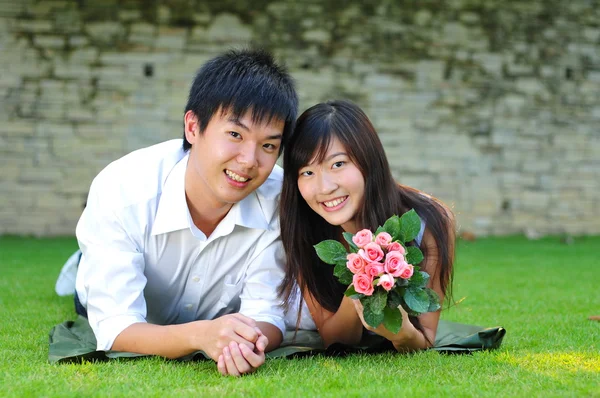 Asiatiska kinesiska par liggande i gräset i kärlek — Stockfoto