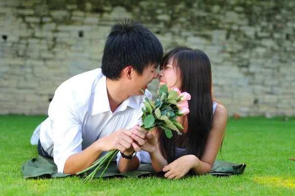 Азиатская китайская пара, лежащая на траве в любви — стоковое фото