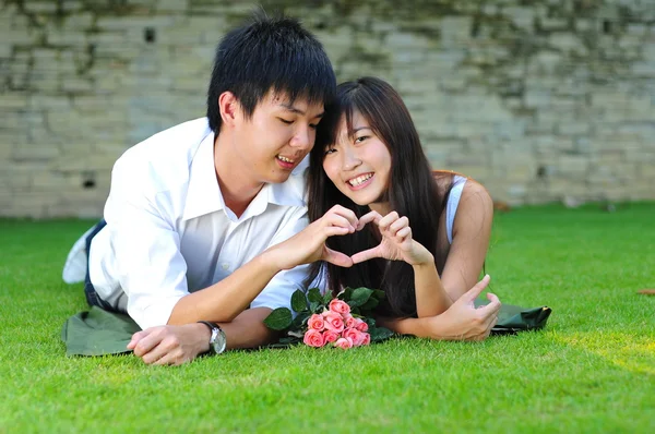 Asijské čínský pár ležící na trávě v lásce — Stock fotografie