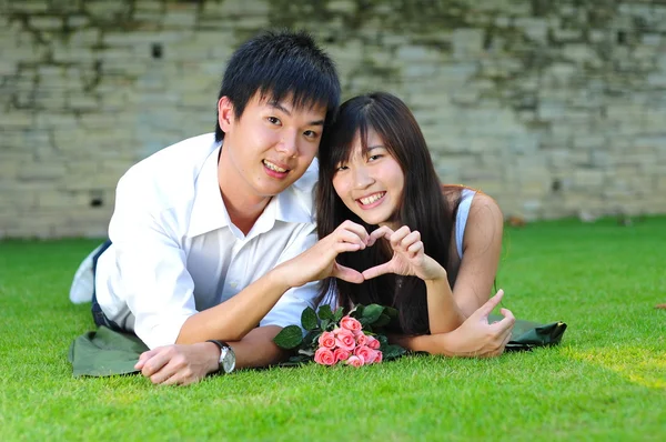Азиатская китайская пара, лежащая на траве в любви — стоковое фото
