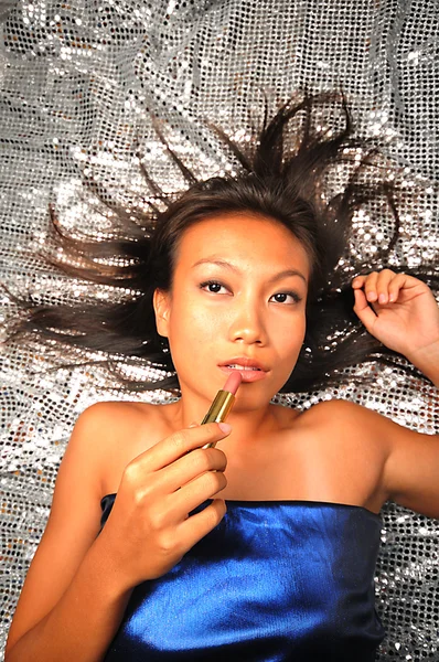 Asiatisk kvinna med ett läppstift som förbereder sig för ett parti — Stockfoto