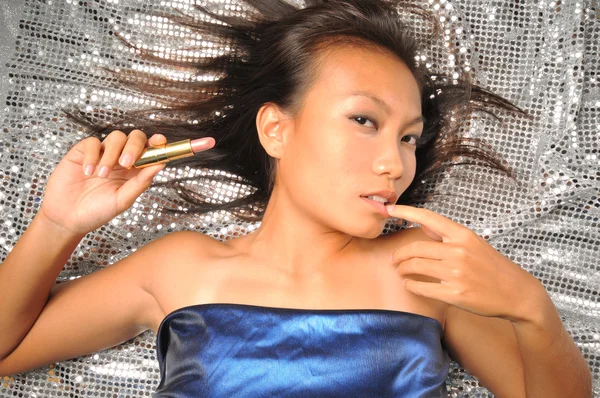 Asiatisk kvinna med ett läppstift som förbereder sig för ett parti — Stockfoto