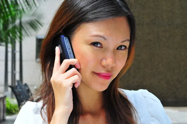 アジアの中国オフィスの女性は彼女のモバイルの communicator を使用して — ストック写真