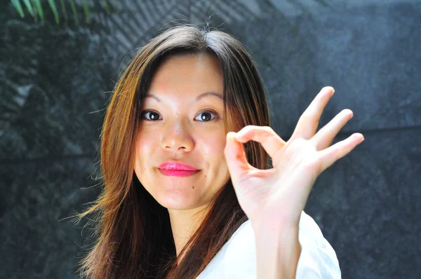 Uśmiechający się azjatycki chiński dziewczynka Dokonywanie znak ok z jej rąk — Zdjęcie stockowe