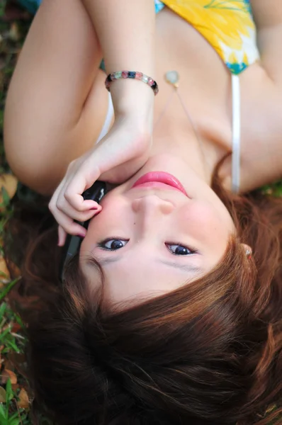 Menina chinesa asiática deitada na grama com seu telefone — Fotografia de Stock