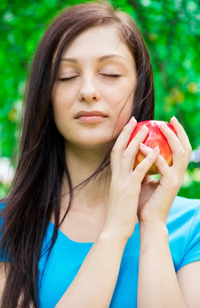 Милая молодая женщина держит яблоко на открытом воздухе — стоковое фото