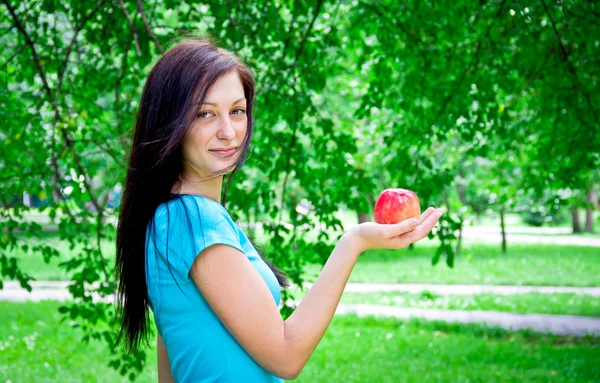 Linda hembra joven sosteniendo una manzana al aire libre —  Fotos de Stock