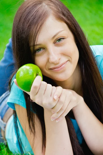 Милая молодая женщина держит яблоко на открытом воздухе — стоковое фото