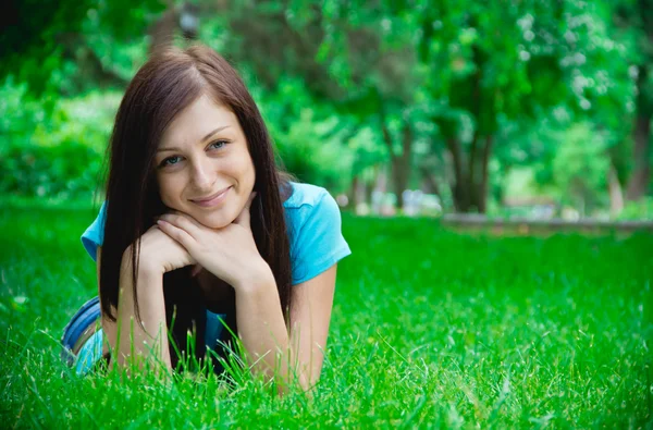 Retrato de uma jovem mulher feliz deitada na grama — Fotografia de Stock