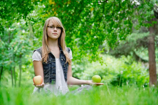 Hermosa chica con las manzanas en la hierba — Foto de Stock