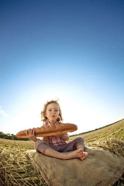 Kind met brood zittend op hayrick — Stockfoto