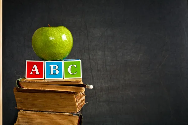 Abc und grüner Apfel auf altem Lehrbuch — Stockfoto