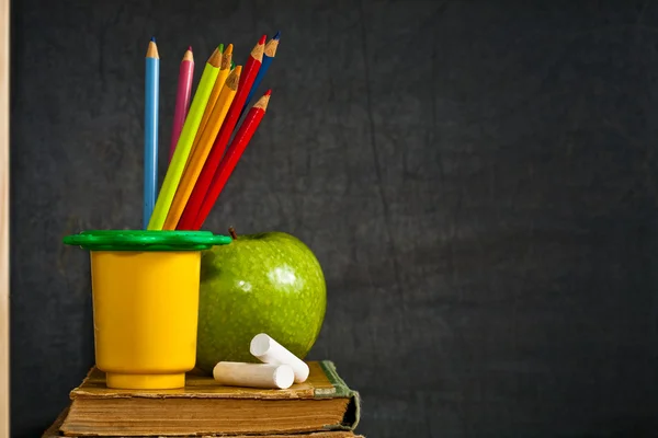Multicolor penna och grönt äpple på gamla lärobok — Stockfoto