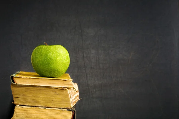 Зеленое яблоко на учебнике — стоковое фото