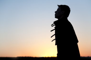 Silhouette of young man at sunset clipart