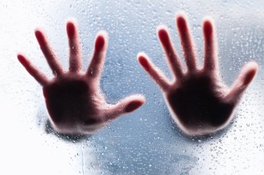 Silhouettes of two right hands behind wet glass clipart