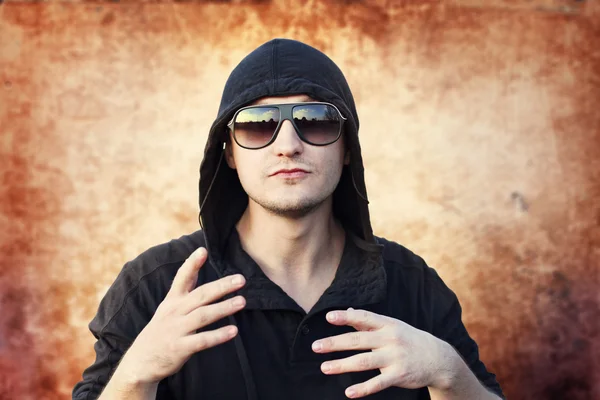 Joven hombre rapero en grunge fondo — Foto de Stock