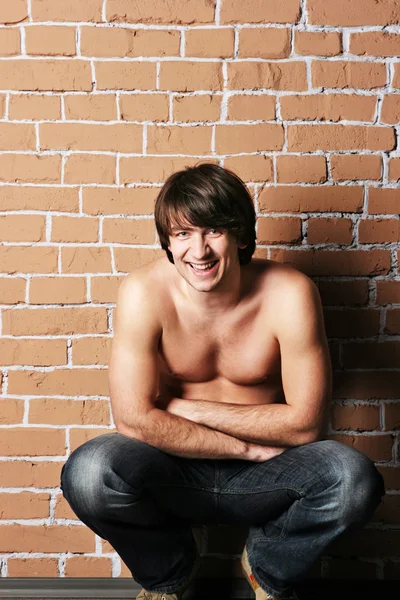 Hombre macho sonriente cerca de una pared de ladrillo —  Fotos de Stock