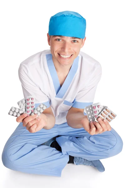 Médico sorridente com comprimidos nas mãos isolados em b branco — Fotografia de Stock