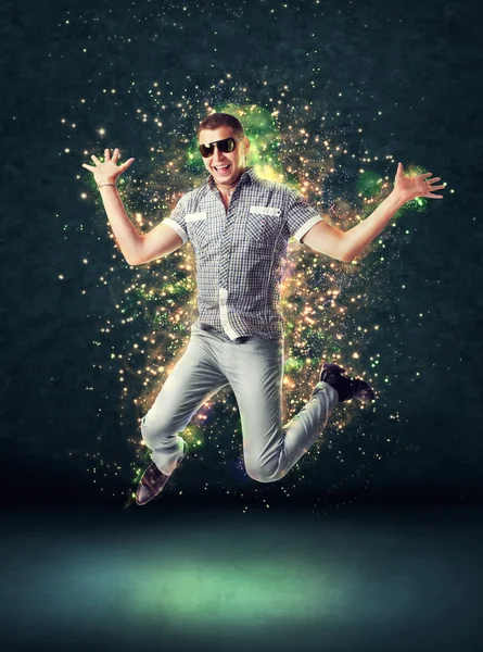 Lachende jonge man springen op gloeiende abstracte achtergrond — Stockfoto