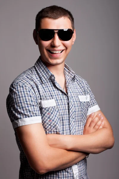 Güneş gözlüklü gülümseyerek mutlu bir genç adam — Stok fotoğraf