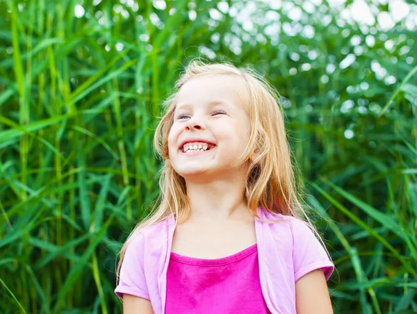 Śmiejąc się blond dziewczynka przed laski w lecie — Zdjęcie stockowe