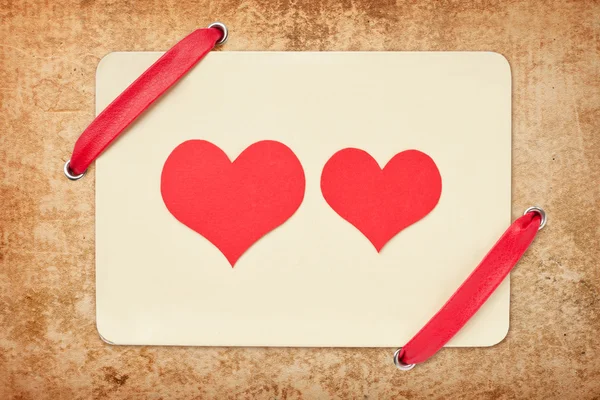 Valentinskarte mit roter Schleife auf Grunge-Papier Hintergrund. zwei r — Stockfoto