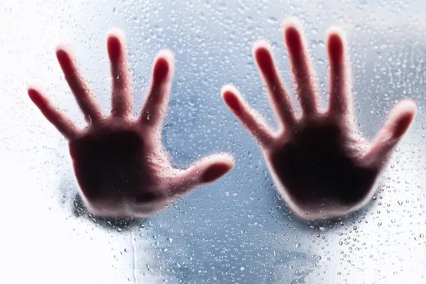 Silhuetter av två rätt händer bakom våta glas — Stockfoto