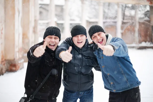 Three happy young men showing thumb up in winter — Zdjęcie stockowe