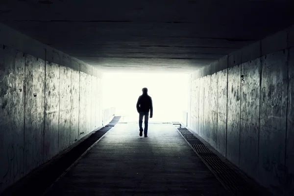 Silhouette of Man Walking in Tunnel (engelsk). Lys ved tunnelens slutt stockbilde
