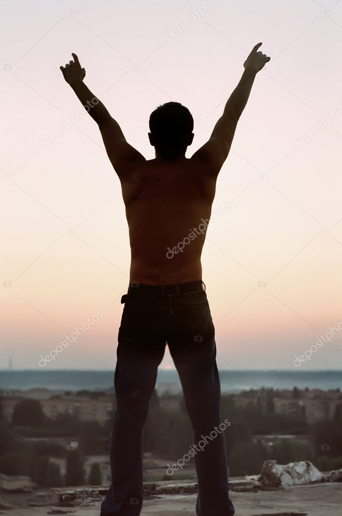 Freedom. Silhouette young man with lifted hands upwards