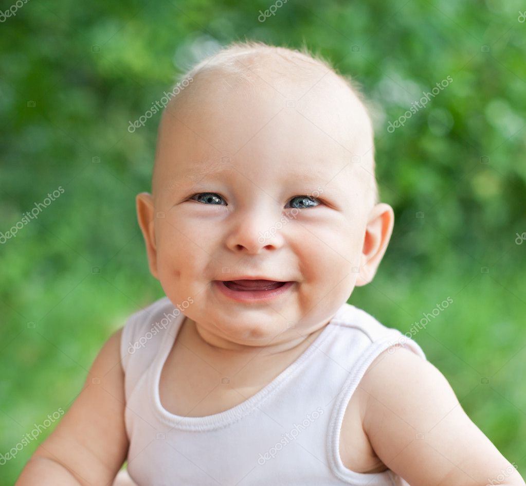 Portrait of smiling happy baby boy on natural background in summ ...