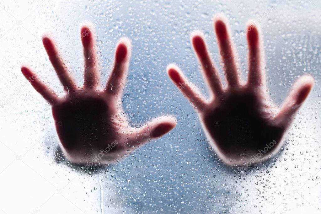 Silhouettes of two right hands behind wet glass