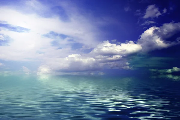 Wolkenloser blauer Himmel, der zum Horizont über einer blauen Meeresoberfläche aufbricht — Stockfoto