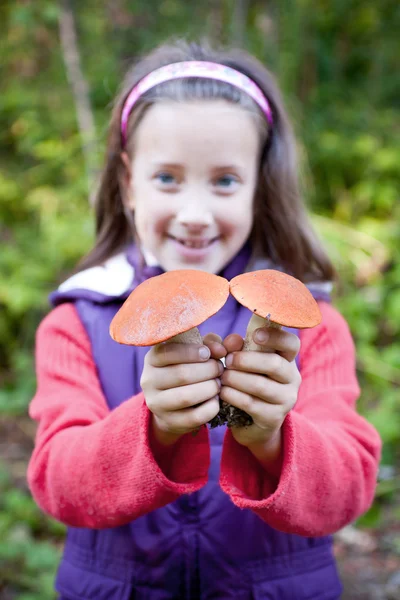Cute smiling little girl holding a mushroom — Stock Photo, Image