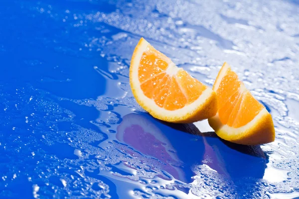 stock image Orange slices on wet blue surface